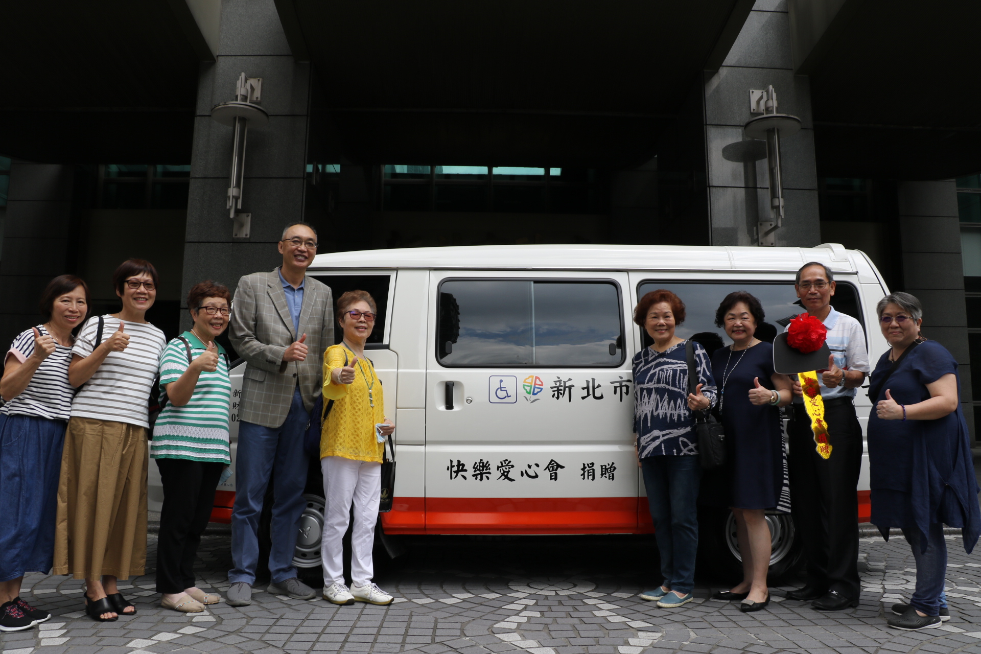 白霞（穿黃色衣服者）率志工好友一起捐贈快樂號復康巴士  左四為謝政達副市長